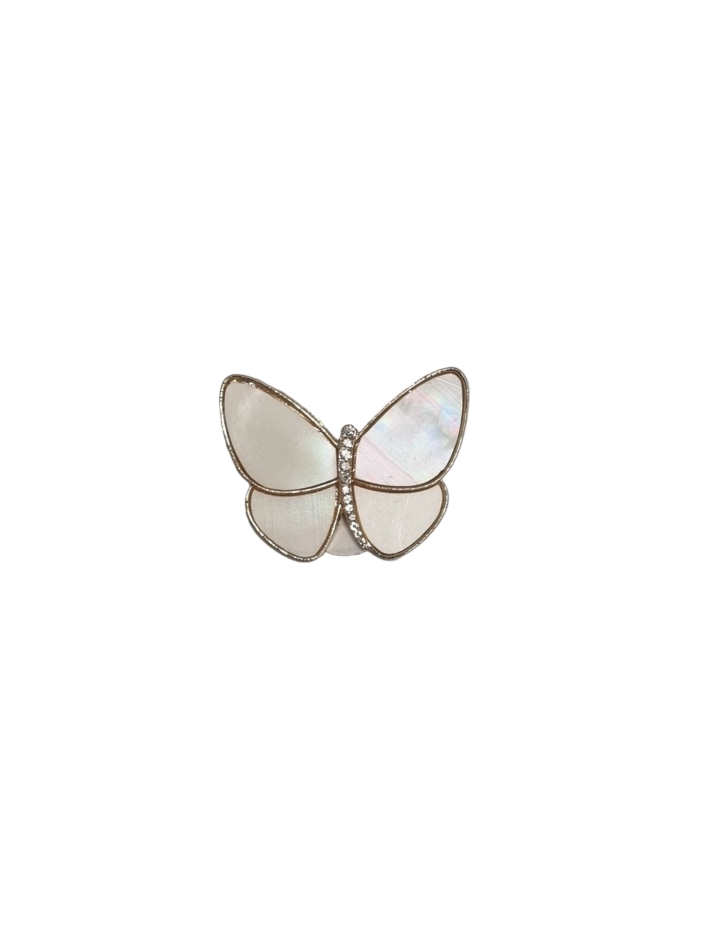 Butterfly-shaped brooch with white and gold details on a gray fabric background