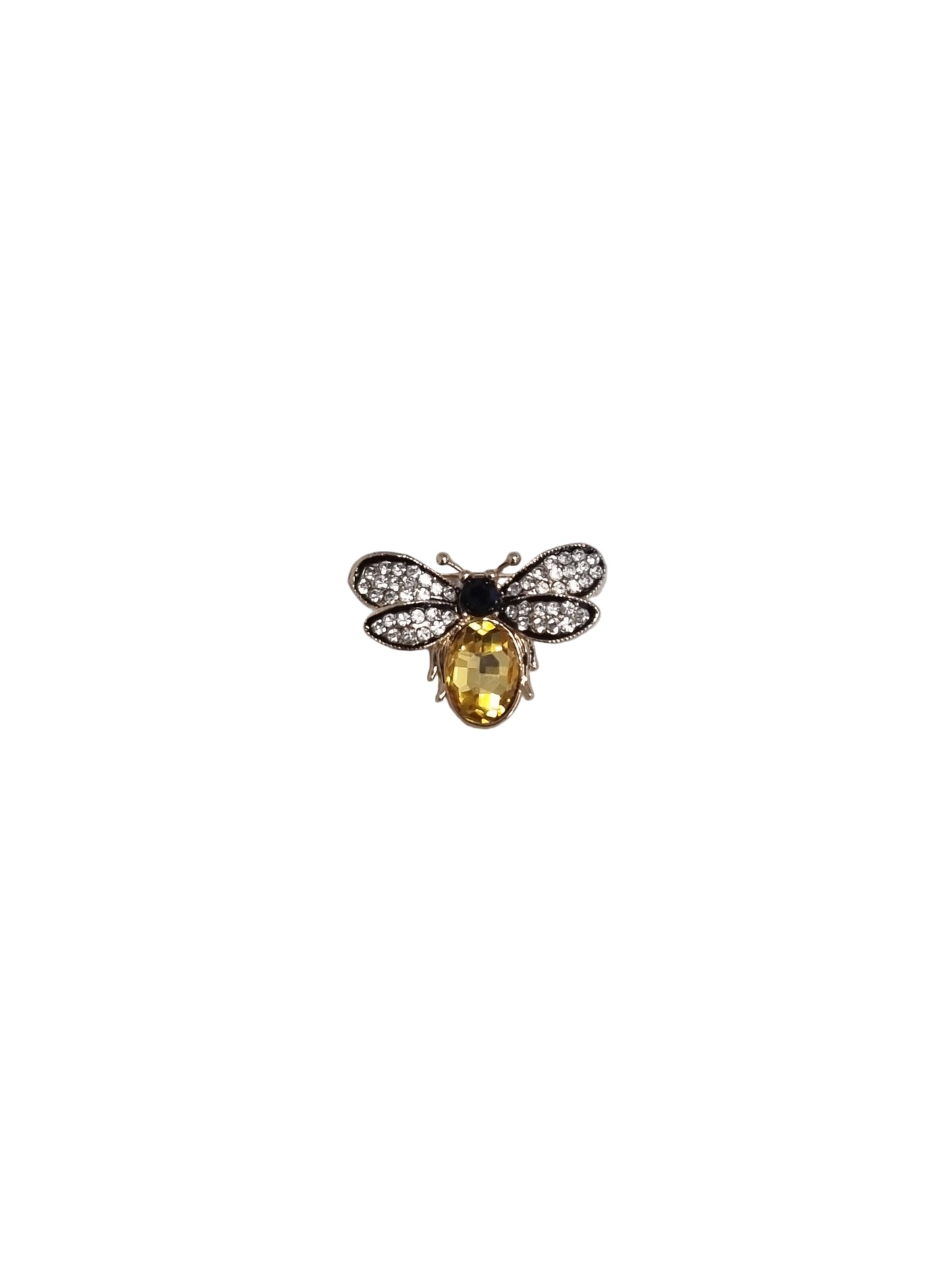 Jewelry brooch with a yellow gemstone and black center on a textured surface
