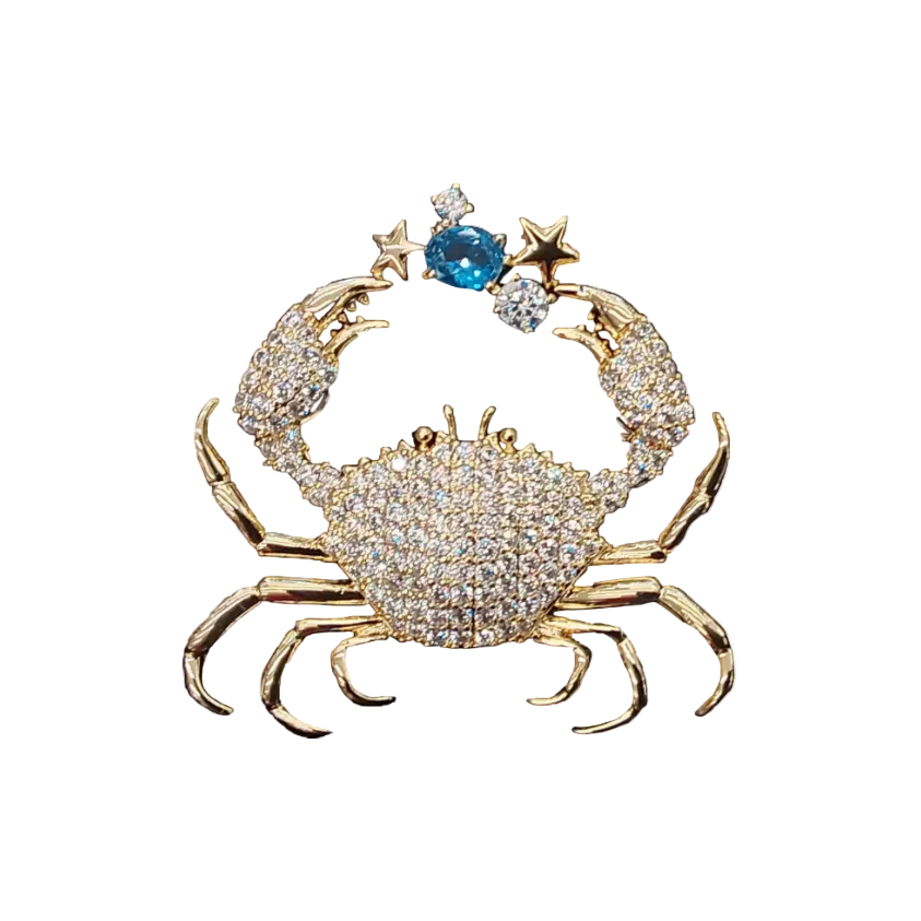 Gold crab-shaped brooch with gemstones on a white background