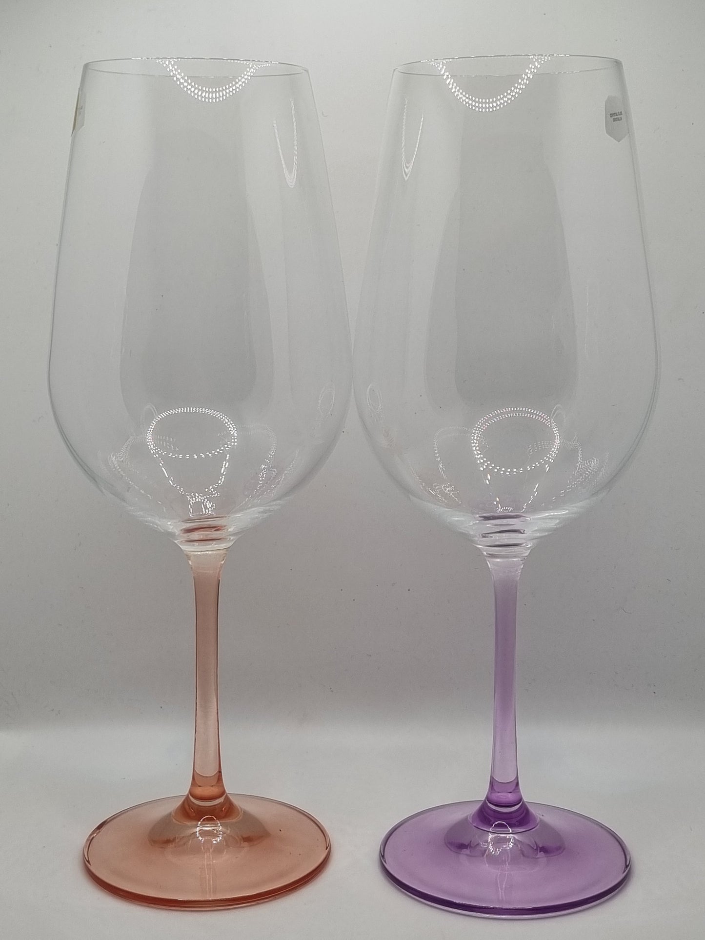 Two red wine glasses with red and purple stems on a white background