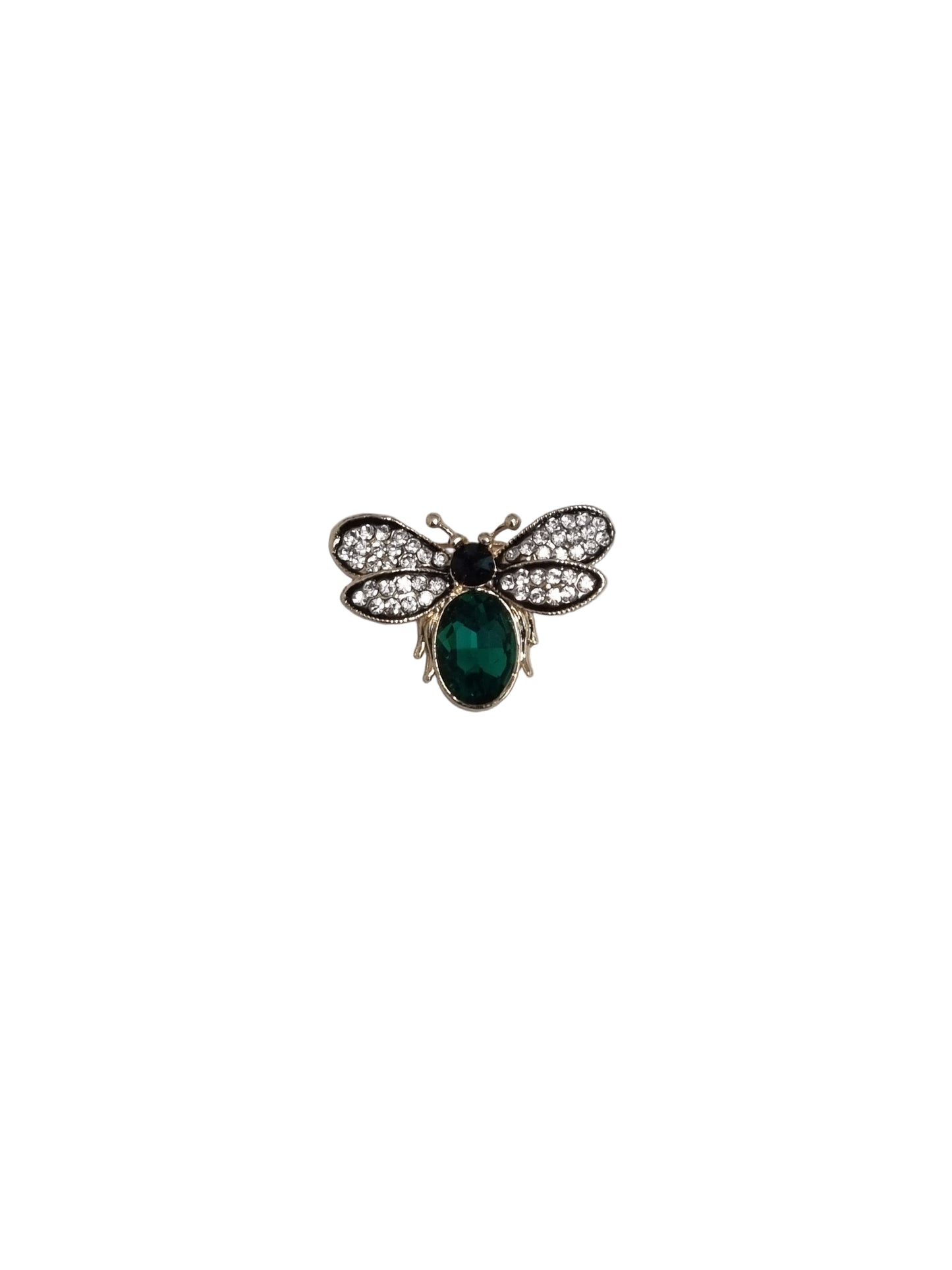 Butterfly-shaped brooch with green gemstone on a textured fabric background