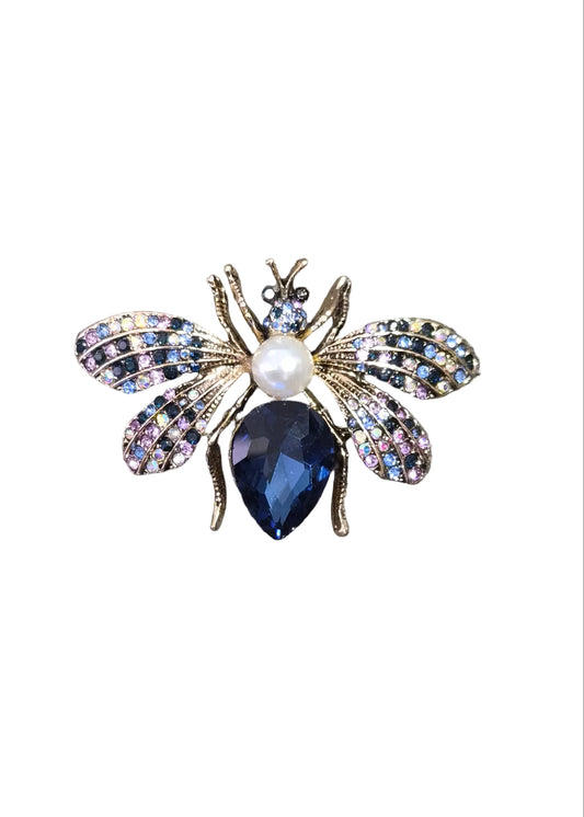 A bee-shaped brooch with iridescent wings, a white pearl center, and a dark blue teardrop crystal