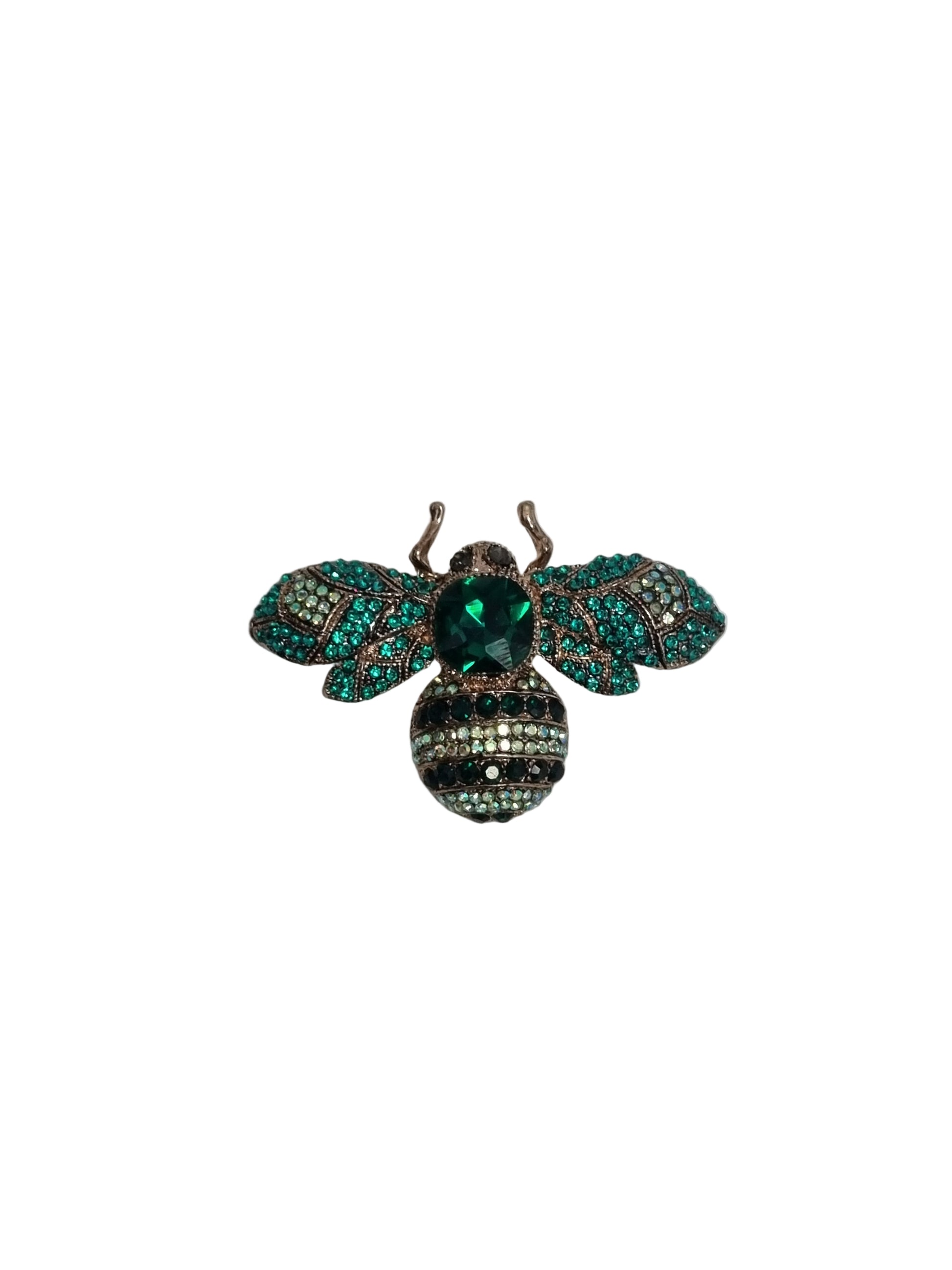 Decorative bee brooch with green and teal gemstones on a white fabric background