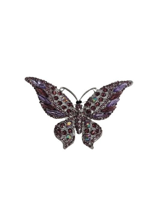 Decorative brooch with purple gemstones on a white fabric background