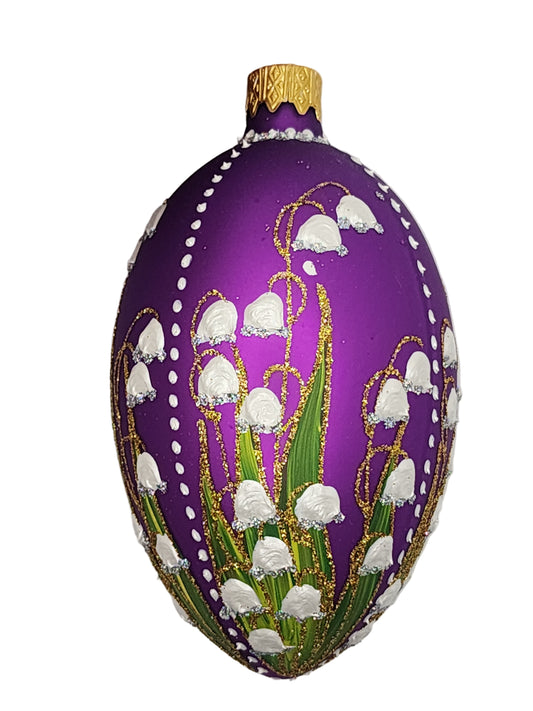Decorative purple egg with gold and green patterns on a white background