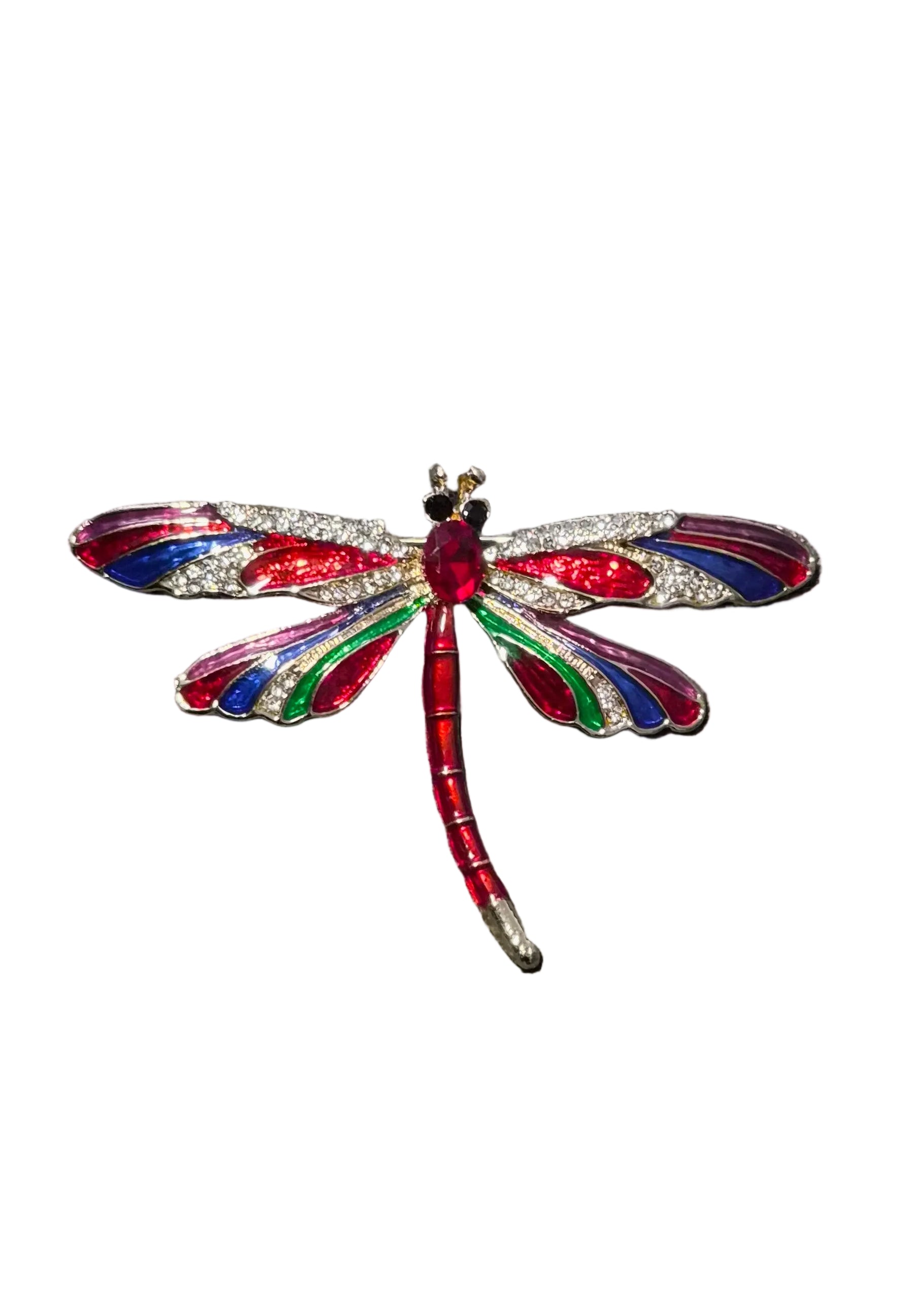 A close-up of a dragonfly-shaped brooch with a red body and multicolored wings in red, blue, green, and silver crystals.